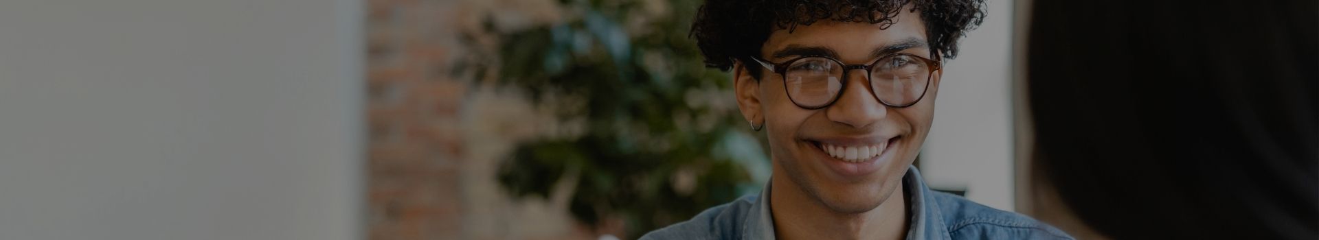 Un jeune homme avec des lunettes parle avec une personne face à lui