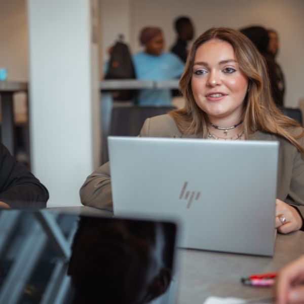 Etudiante en Mastère Management de projet Jeune femme blonde assise devant un bureau avec un ordinateur portable
