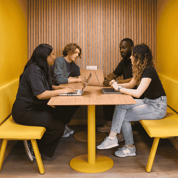 Etudiants de l'ESGCI en projet de groupe Groupe d'étudiants autour d'une table travaille sur un projet de groupe dans une salle jaune