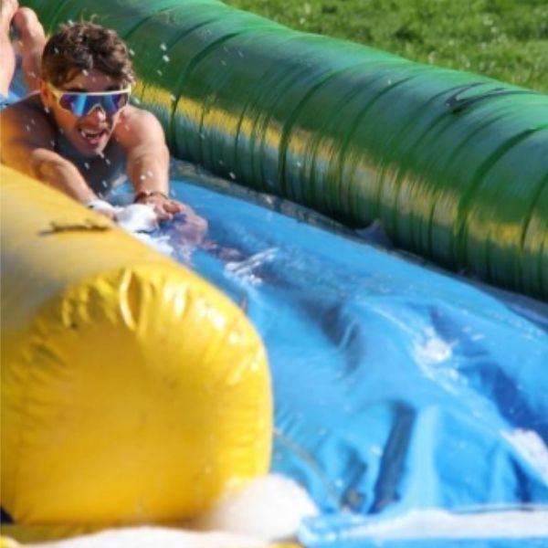 Etudiant de l'ESGCI glissant sur le ventre face caméra sur un toboggan moussant